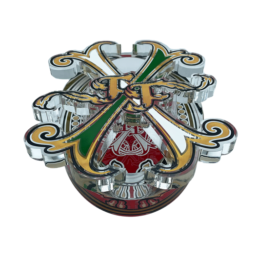 A highly detailed, chrome-plated metal toy or collectible emblem featuring crossed green and gold swords, a red central shield with white script, and ornate gold scrollwork on a white background.