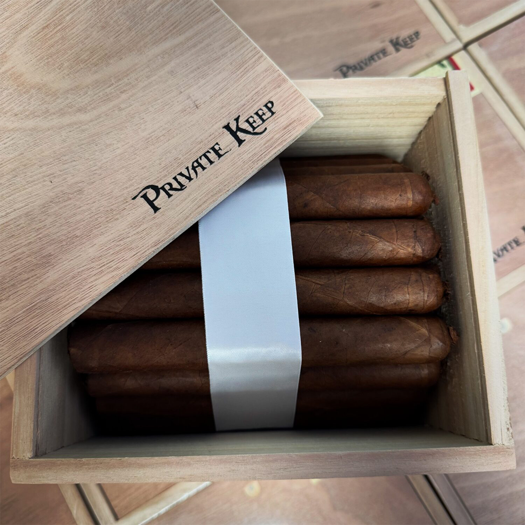 Open wooden box of cigars with 'Private Keep' branding.